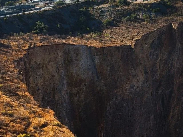 Une mine à ciel ouvert escarpée et profonde, la mine de diamants de Cullinan, entourée d'un terrain aride.