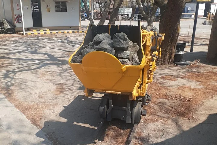 Un piccolo carrello minerario giallo pieno di rocce esposto all'aperto su binari.