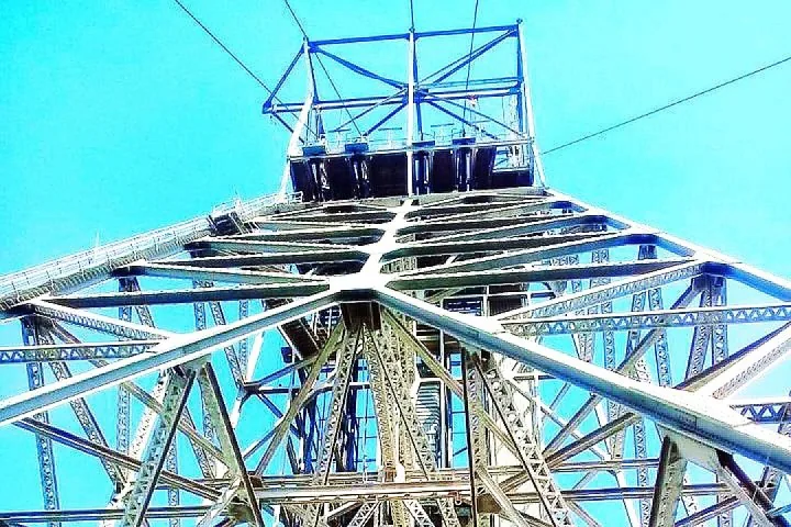 Vista hacia arriba de una gran estructura de acero de un castillete contra un cielo azul despejado.