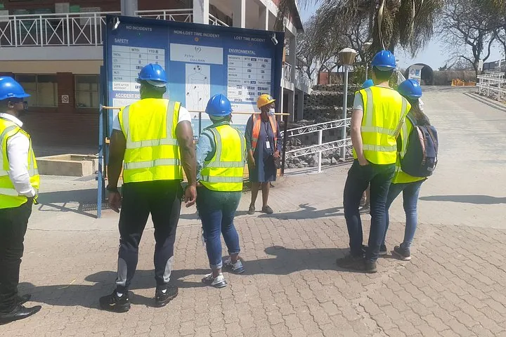 A group of visitors in safety gear looking at an information board outside.