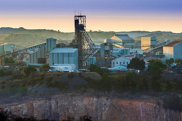 Industrieanlagen und Fördergerüst einer Mine im warmen Licht des Sonnenaufgangs.